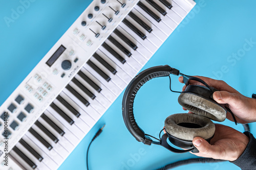 Headphones in male hands against the background of musical keys, top view.