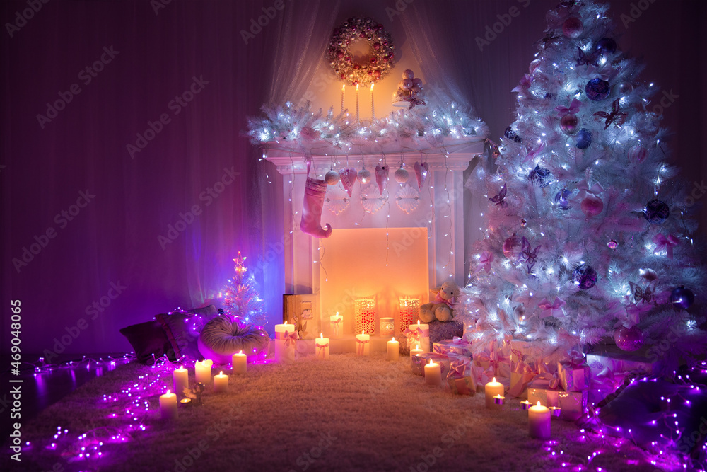 Christmas Home Room Interior with Fire Place Candle Light and White Xmas Fir Tree Decorated with Pink Ornaments and Purple Garland Lights. Cozy Winter Holiday Night Decoration Indoor Design