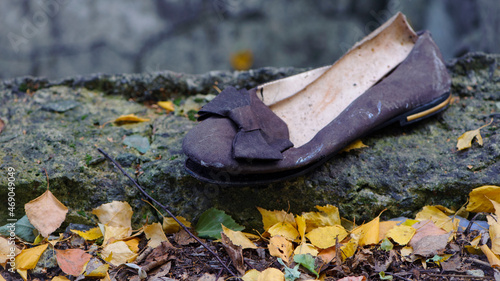 Old torn, but previously stylish women's shoes. worn out shoes. summer shoes with a bow. thrown in the street, in the autumn leaves. the concept of poverty, there is nothing to put on. close-up