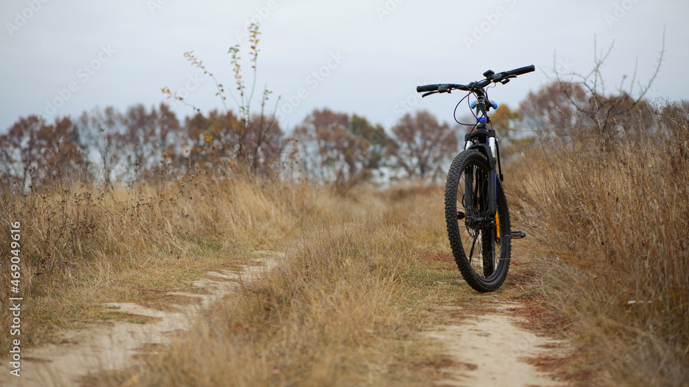 bike stands on in the field. A mountain bike stands on a field path with dry autumn grass. cycling. Mountain bike. outdoor cycling activities. active rest, sports, travel. space for text bike stands on in the field. A mountain bike stands on a field path with dry autumn grass. cycling. Mountain bike. outdoor cycling activities. active rest, sports, travel. space for text