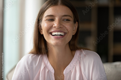 Head shot happy millennial attractive Caucasian woman having fun holding video call conversation  communicating distantly  feeling joyful hearing good news  showing positive sincere emotions.