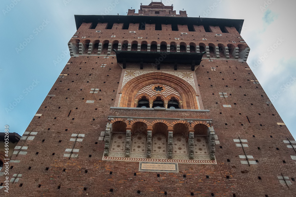 Entrance to the Sforza Castle in Milan, Lombardy. Filarete Tower, La torre del Filarete and brick walls of old medieval Sforza Castle Castello Sforzesco and cloudy sky background.