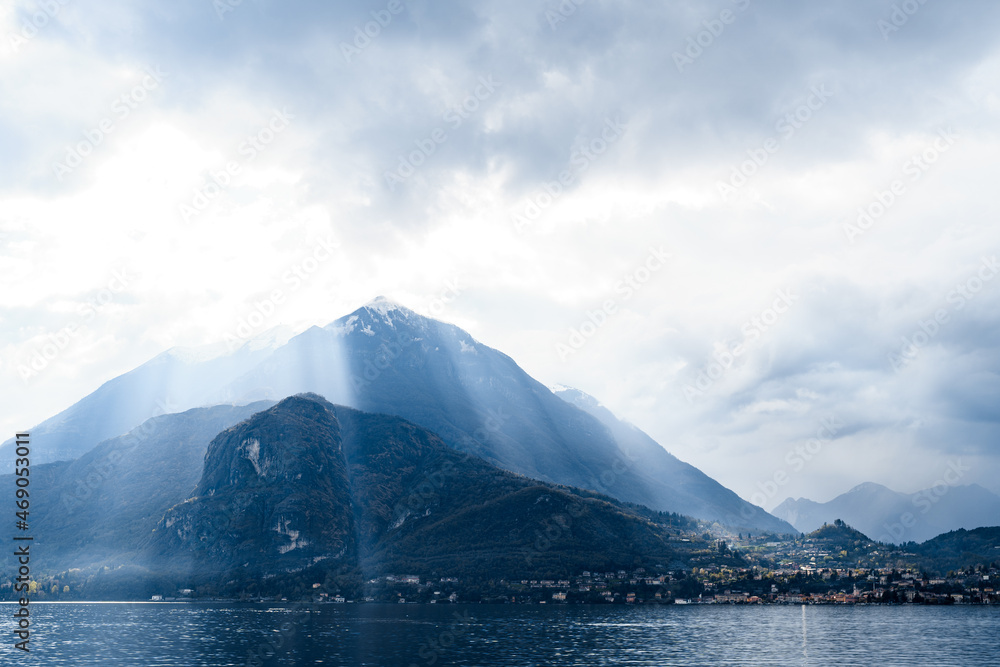 Sun shines through the clouds over the mountain tops. Lake Como, Italy