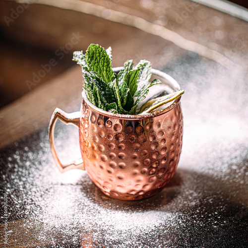 Copper mug of fresh cocktail with mint and powdered sugar photo