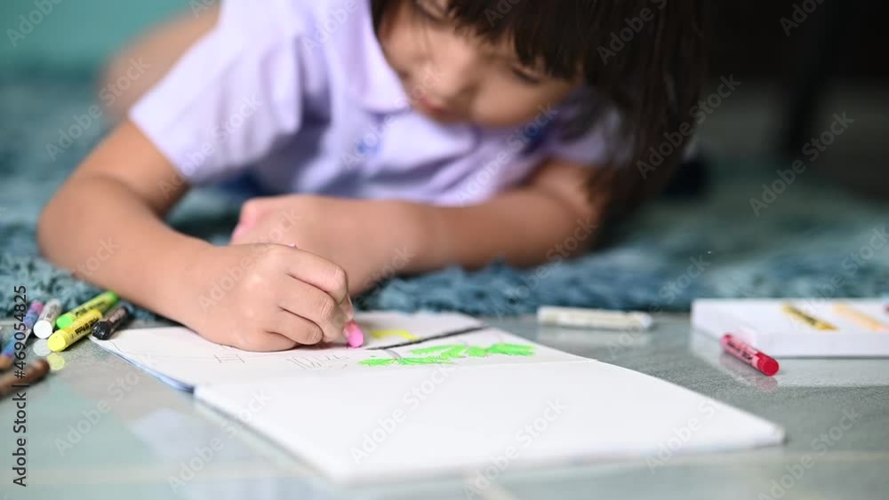little girl writing and coloring with chalk crayon while relaxing on carpet at home after comeback from school little girl writing and coloring with chalk crayon while relaxing on carpet at home after comeback from school