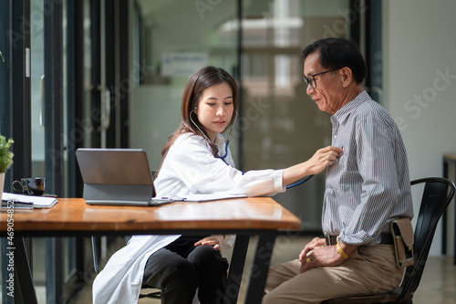 Asian female doctor using stethoscope exam elderly male patient for physical examine pneumonia lung sound checkup in hospital.