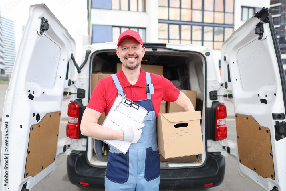 Smiling man holding a box and a delivery document Smiling man holding a box and a delivery document