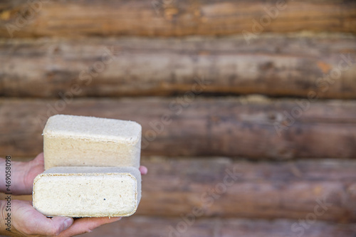 Hands hold fuel briquettes made from sawdust. Selective focusing on the briquette in the lower left corner of the frame. photo