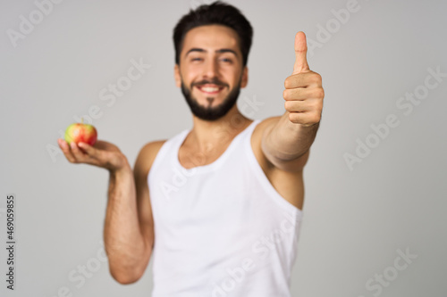 a man in a white t-shirt fresh fruit apples vitamins light background