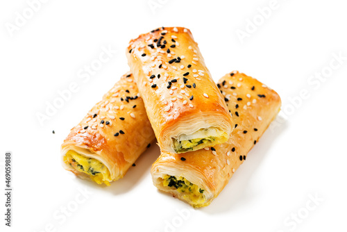 Turkish borek rolls with spinach and cheese. A traditional Turkish pastry rulo borek with black and white sesame seeds. Isolated on white background. photo