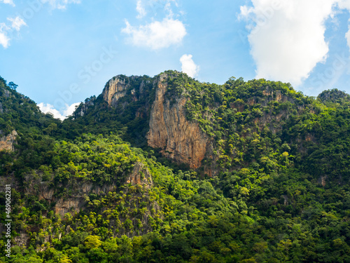 Nature background. Green tree, jungle on the beautiful shape mountain on blue sky and fluffy cloud with sunshine on sunny day.