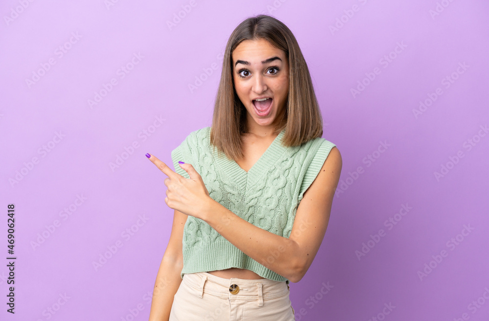 Young caucasian woman isolated on purple background surprised and pointing side Young caucasian woman isolated on purple background surprised and pointing side