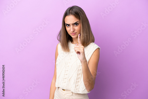 Young caucasian woman isolated on purple background frustrated and pointing to the front