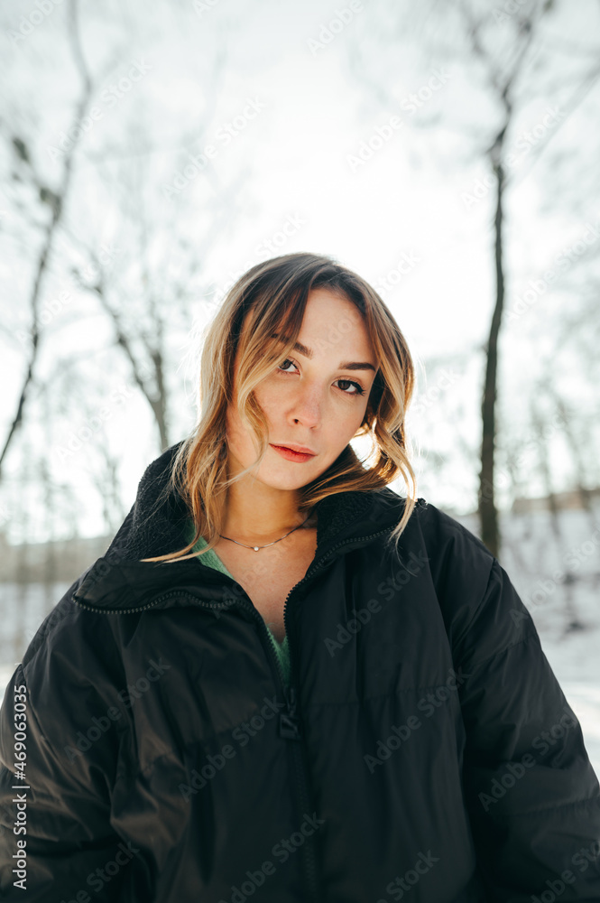 Portrait of a stylish lady in warm casual clothes on a walk in the winter forest in sunny weather, posing for the camera with a serious face. Portrait of a stylish lady in warm casual clothes on a walk in the winter forest in sunny weather, posing for the camera with a serious face.