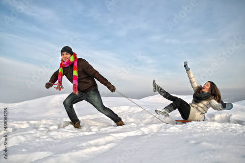 Man pulling girl on a sled at snow (concept: Winter fun)