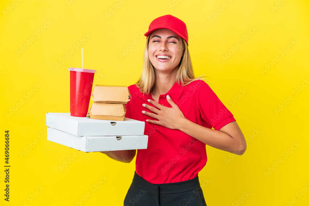 Delivery Uruguayan woman holding fast food isolated on yellow background smiling a lot Delivery Uruguayan woman holding fast food isolated on yellow background smiling a lot