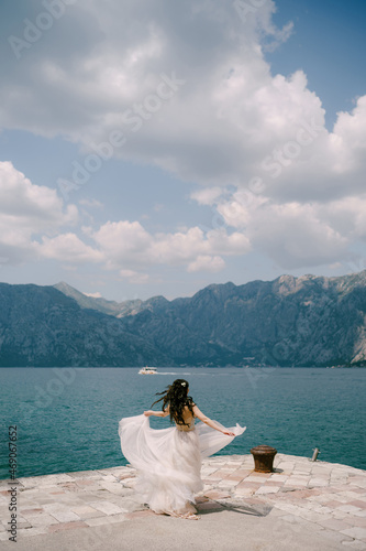 The bride spins on the pier in the Bay of Kotor, her skirt flutters around her 