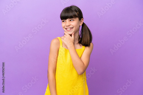Little caucasian kid isolated on purple background looking to the side and smiling