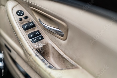 Malted and dirty car door hand rail close up. Interior vehicle window control panel.