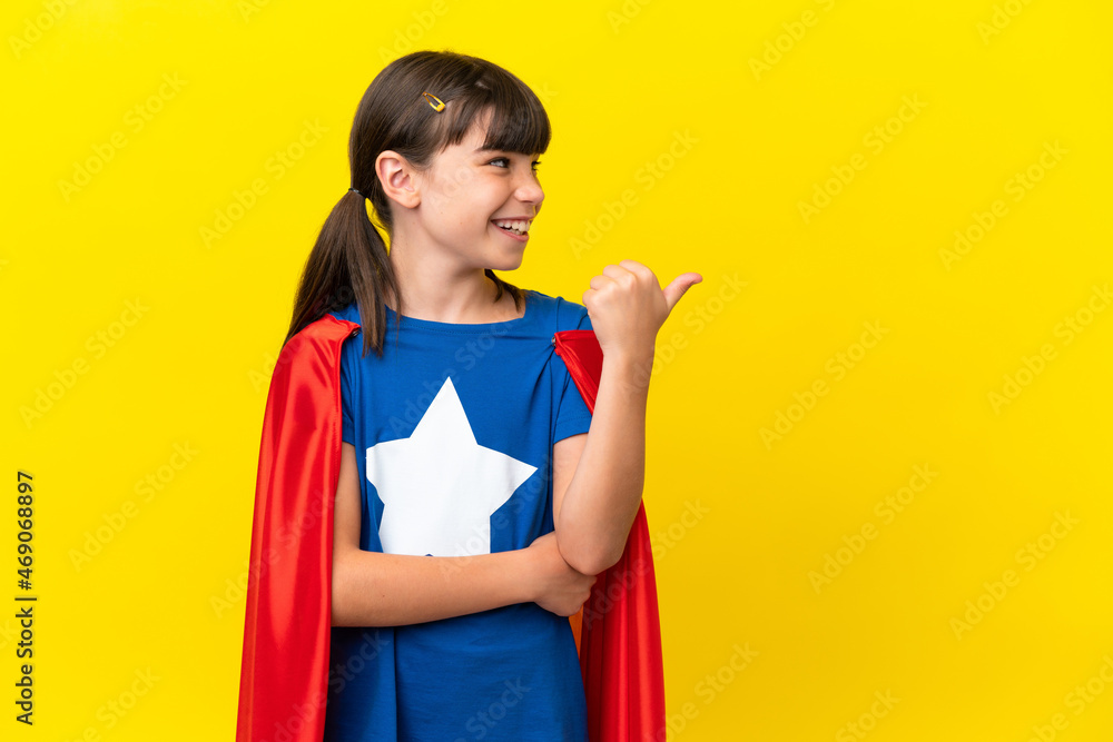 Little super hero kid isolated on purple background pointing to the side to present a product Little super hero kid isolated on purple background pointing to the side to present a product