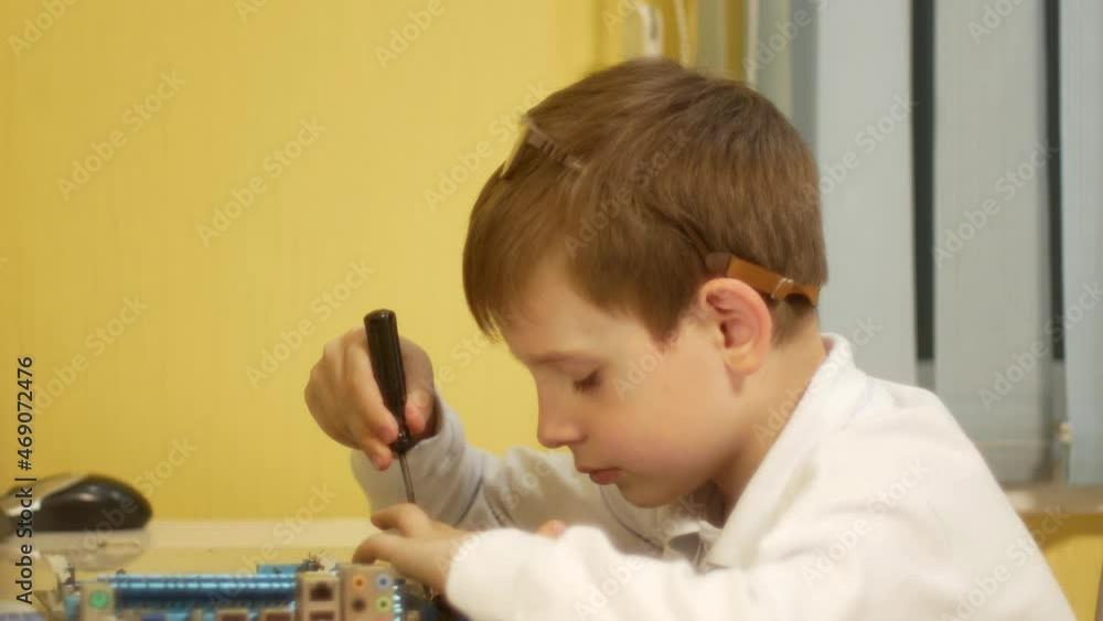 Child little handyman theme. Caucasian boy, 7-8 years old, repairs household appliances with a screwdriver. Child inquisitive home craftsman engineer repairing computer at home Child little handyman theme. Caucasian boy, 7-8 years old, repairs household appliances with a screwdriver. Child inquisitive home craftsman engineer repairing computer at home