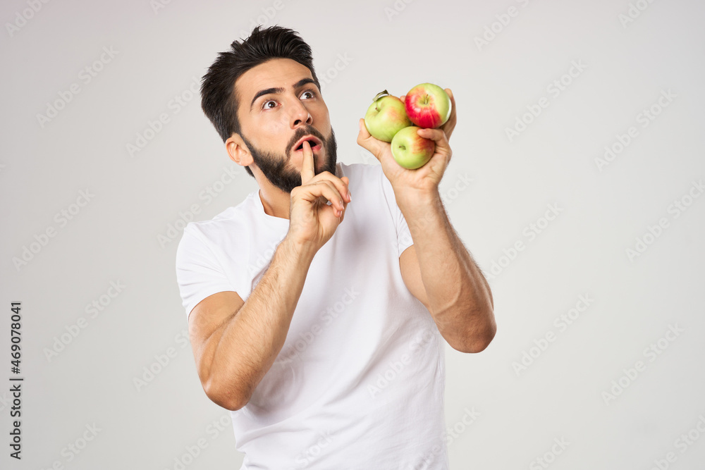 Cheerful man with apples in his hands in a white t-shirt fruits Cheerful man with apples in his hands in a white t-shirt fruits