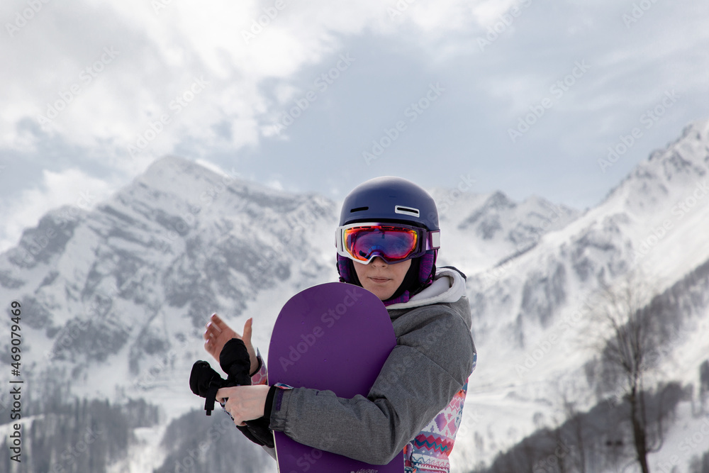 Portrait of a girl with snowboards in a helmet and goggles
