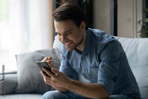 Happy millennial man making yes gesture looking at cellphone screen, celebrating getting online lottery auction win notification, reading message with amazing victory news, internet success concept.