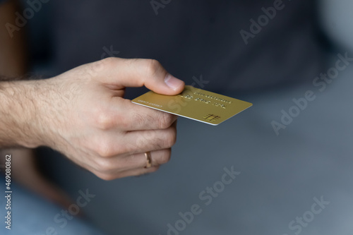Close up young man holding plastic credit card in hand, buying goods with wireless payment service, shopping without cash, contactless financial operations, cashless secure purchases concept.