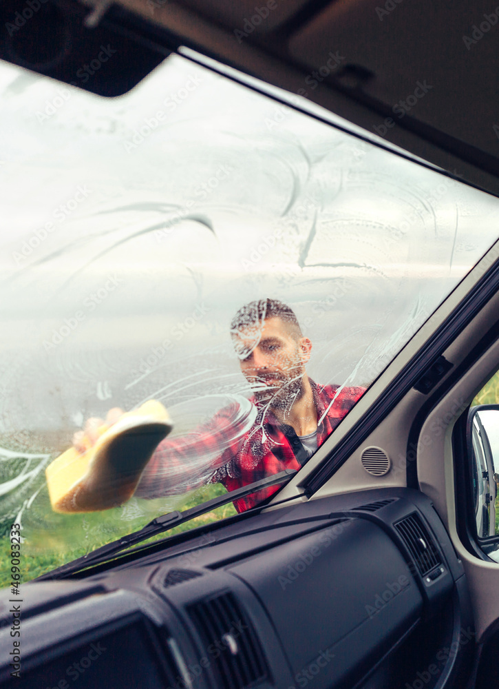 Young man cleaning motorhome glass with sponge outdoor Young man cleaning motorhome glass with sponge outdoor