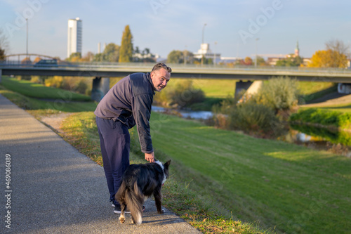 Sporty man holding the collar of his Border Collie dog