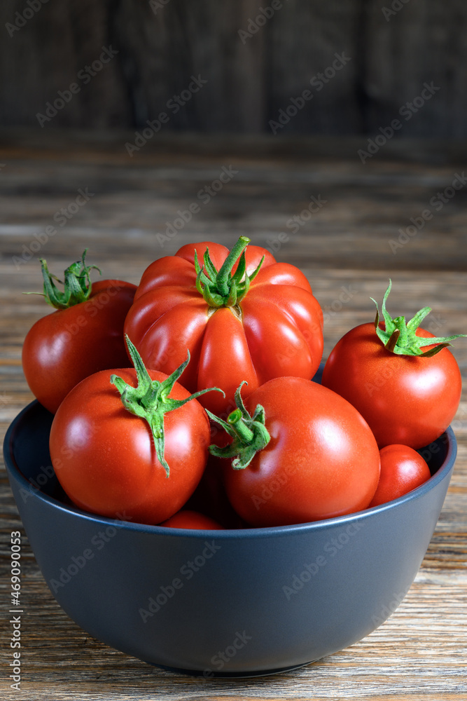 Ripe organic red tomatoes in a bowl on rustic wooden table. Ripe organic red tomatoes in a bowl on rustic wooden table.