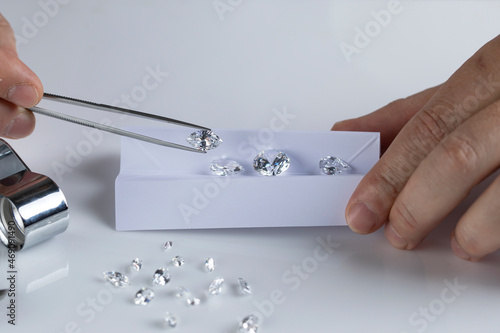 Billede på lærred Close up of diamond expert's hand at workplace evaluating gemstones polished diamonds