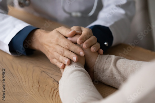 Close up cropped of young female doctor therapist holding mature patient hands at meeting  giving psychological help  supporting comforting  bad medical checkup results and health problem concept