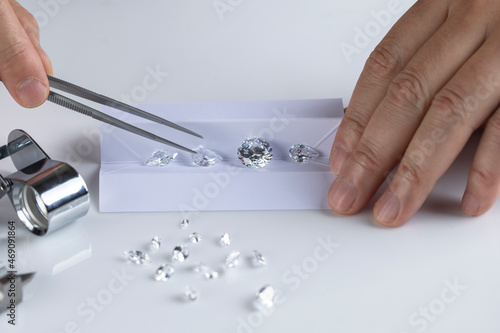 Close up of diamond expert's hand at workplace evaluating gemstones polished diamonds. High quality photo photo