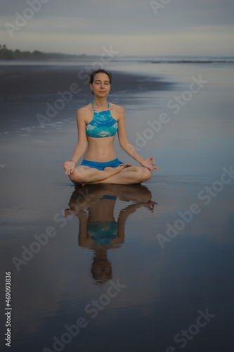 Beach yoga practice in Bali. Lotus pose. Padmasana. Hands in gyan mudra. Meditation and concentration. Zen life. Relaxation of body and mind. Yoga retreat. Water reflection. Copy space.