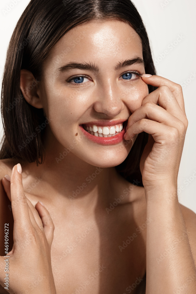 Beauty face. Smiling woman touching healthy skin portrait. Beautiful happy girl model with fresh glowing hydrated facial skin and natural makeup on white background at studio. Skin care concept Beauty face. Smiling woman touching healthy skin portrait. Beautiful happy girl model with fresh glowing hydrated facial skin and natural makeup on white background at studio. Skin care concept