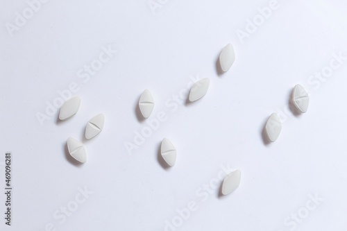 scattered white pills on white reflective background