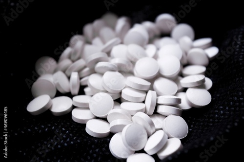 scattered white pills on white reflective background