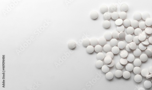 scattered white pills on white reflective background
