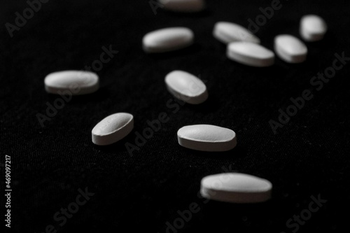 scattered white pills on black background