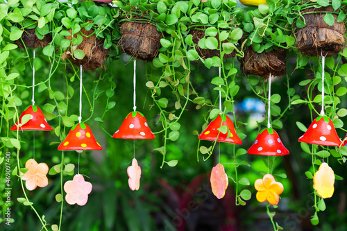 green ivy with red strawberry wind chime tile or small bell hangs in the garden without people and natural bushes beauty or trees for architecture decor and freshness at home photo