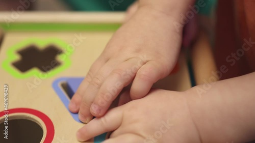 little baby kids brothers hands playing with wooden Montessori educational blocks shape sorter toy. children home learning match different color cubes to shape holes. early Infant developing concept