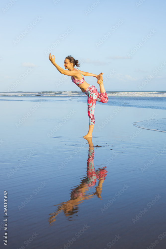 Beach yoga practice. Woman standing in Natarajasana, Lord of the Dance