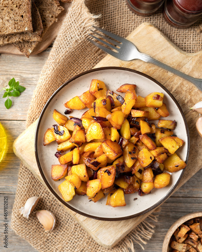 Fried potatoes in a plate on a gray wooden table top view