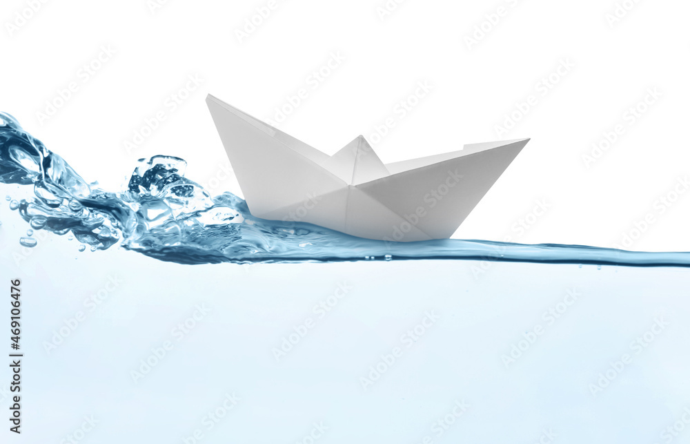 Obraz premium Handmade paper boat floating on clear water against white background