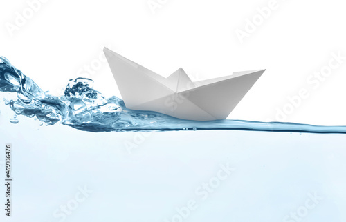 Handmade paper boat floating on clear water against white background
