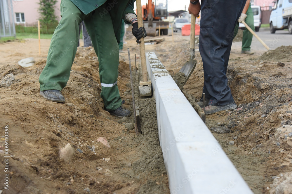 Workers are installing concrete curbs in cement, building a road. Workers are installing concrete curbs in cement, building a road.