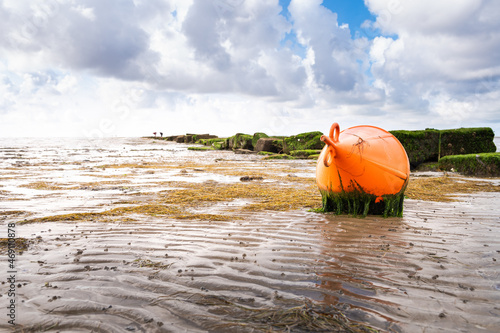 A bright red buoy lies on the mudflat in Dagebüll in Schleswigholstein at low tide
