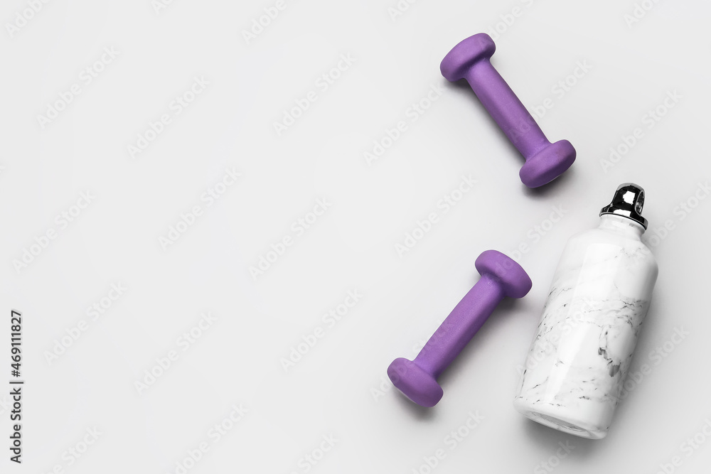 Dumbbells and bottle of water on light background Dumbbells and bottle of water on light background